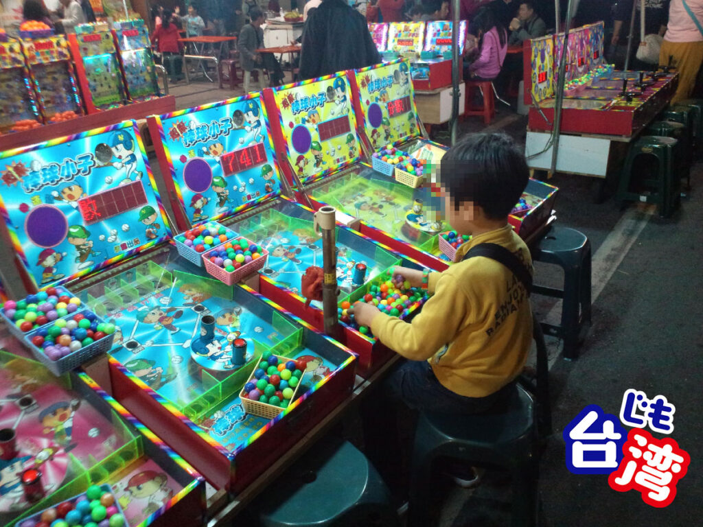 2012年の台湾・高雄の六合夜市にて、野球をテーマにしたレトロなピンボール風のゲーム屋台で遊ぶ子供の様子